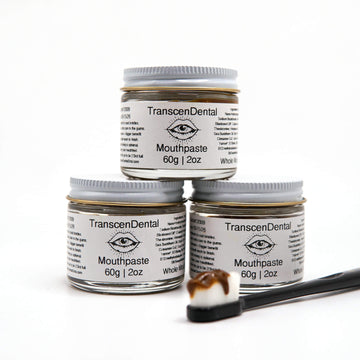 Three jars of TranscenDental 10% nano-hydroxyapatite toothpaste with a toothbrush